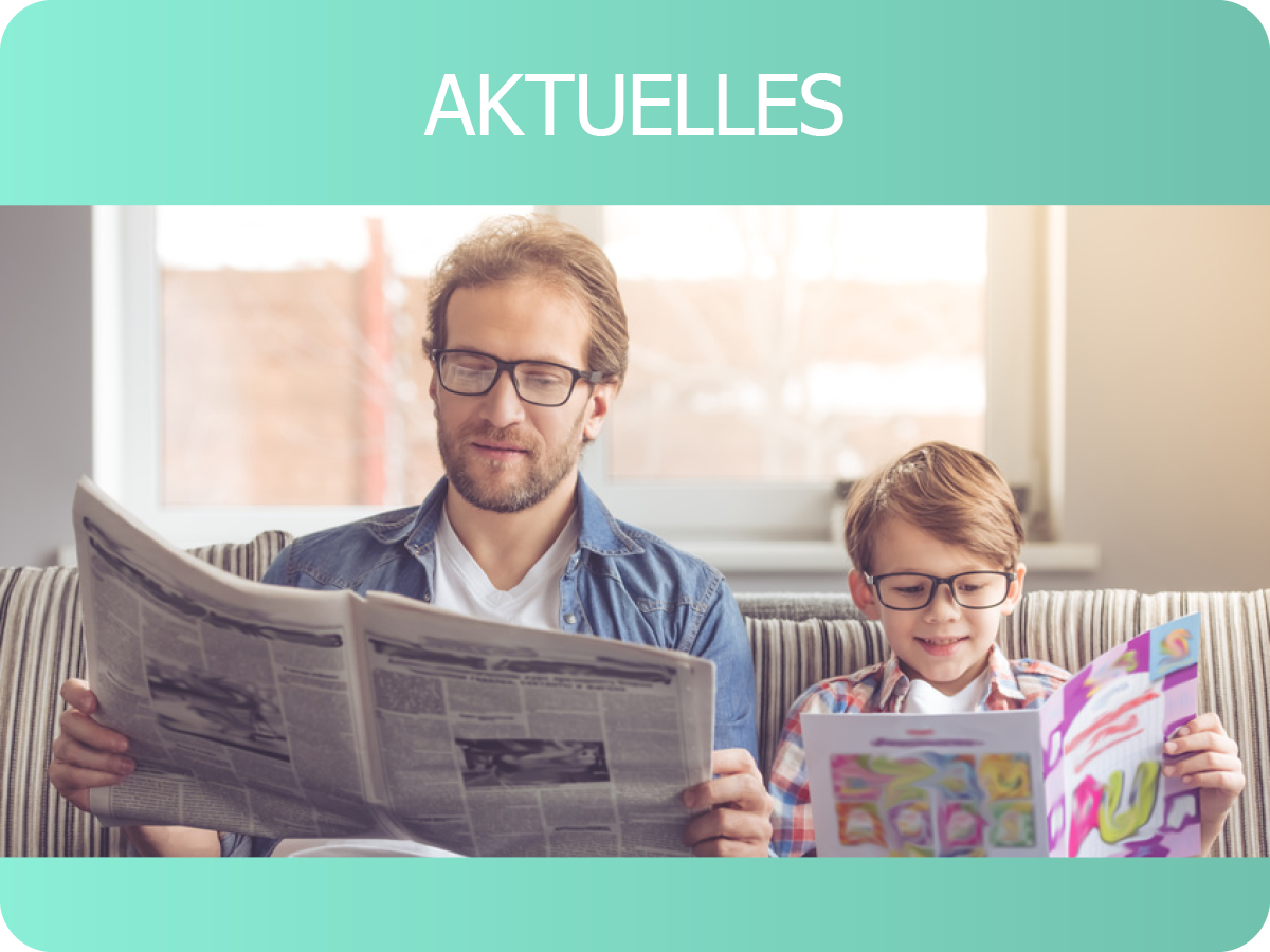 Vater mit Sohn lesen gemeinsam Zeitung auf dem Sofa