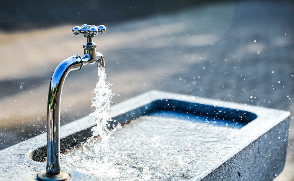Sprudelnder Wasserhahnen an einem Brunnen