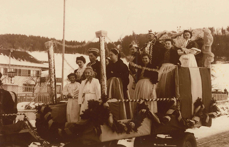 Historische Aufnahme bei einer Faschingsveranstaltung. Mit einem dekoriertem und geschmückten Wagen und verkleideten Personen