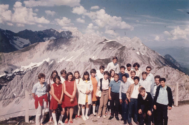 Personen bei einem Ausflug in die Berge welche ein Gruppenfoto gemacht haben vor dem Bergpanorama