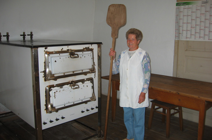 Frau mit Backschaufel vor dem Backofen beim Brot backen