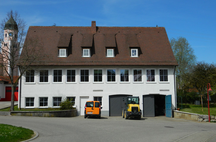 Aufnahme der alten Kochschule und dem Bauhof der Gemeinde Straßberg. Davor steht ein Radlader und ein Gemeindefahrzeug