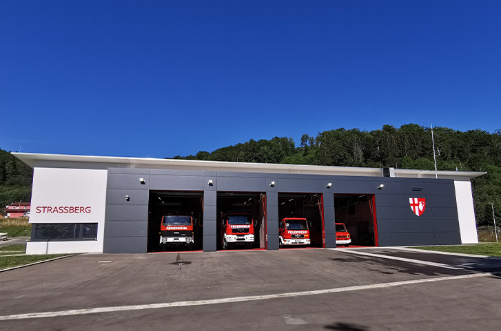 Ein Feuerwehrhaus mit geöffneten Toren der Fahrzeughalle
