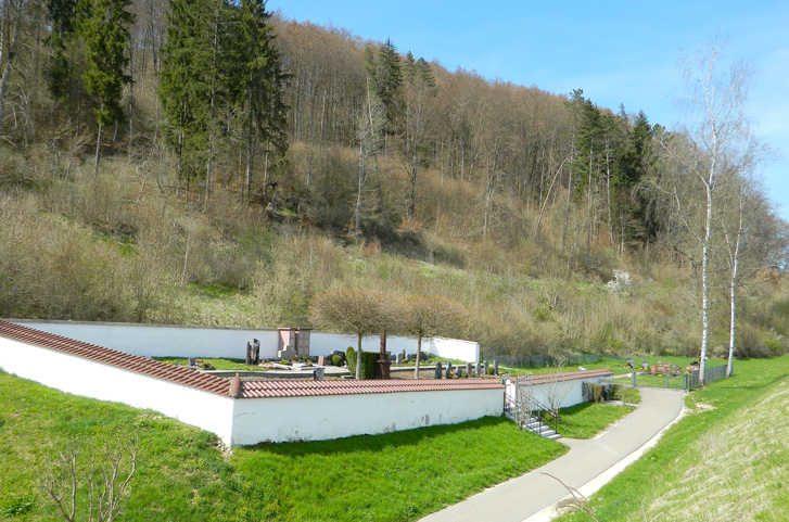 Ein Friedhof mit angelegten Gräbern und weißer Friedhofsmauer