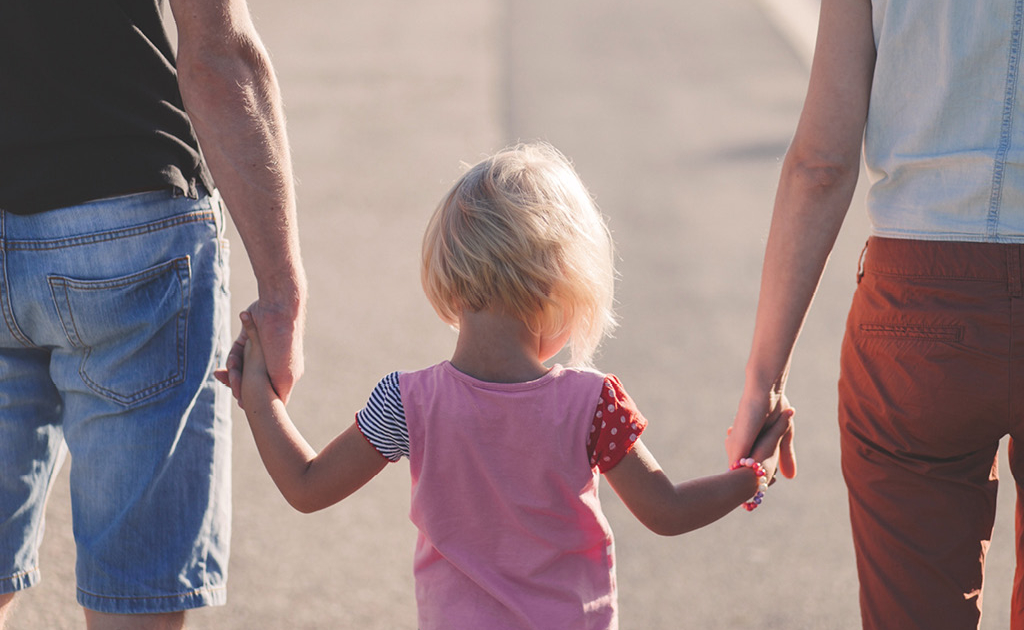 Vater und Mutter die ihr Kind in der Mitte an den Armen halten
