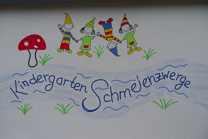 Zeichnung an einer Fassade mit bunten Zwergen und dem Schriftzug Kindergarten Schmeienzwerge
