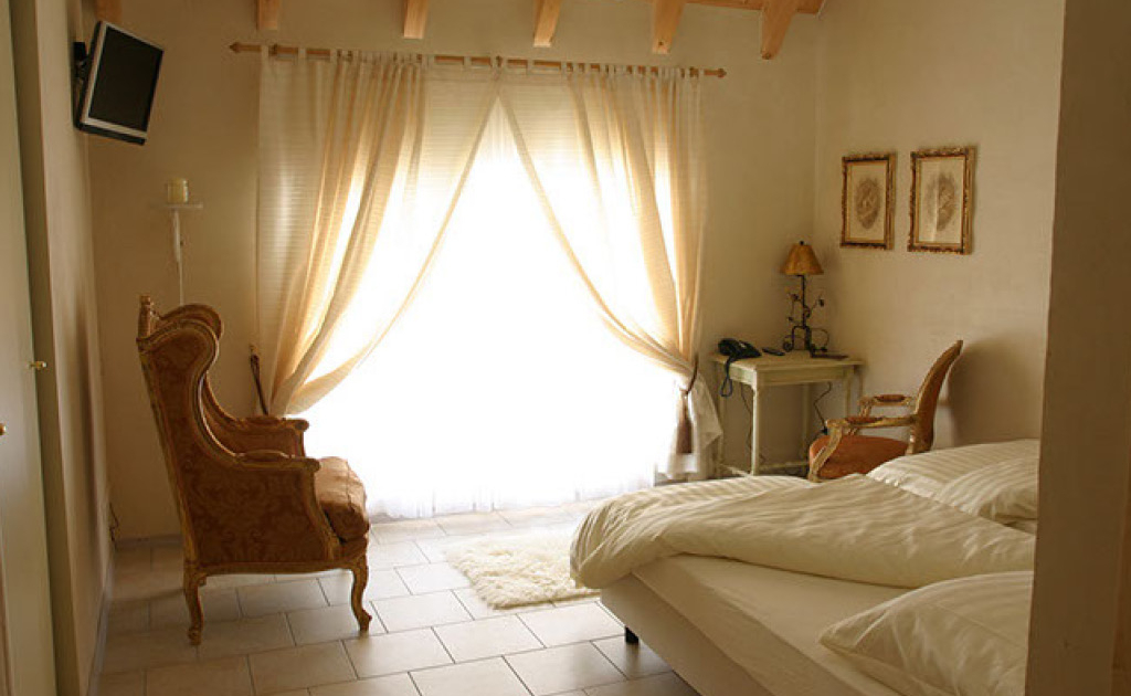 Blick in ein Schlafzimmer mit Sessel und Bett